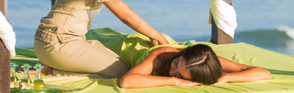 Una mujer disfruta de un masaje en la playa.