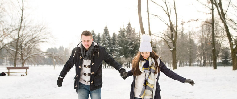Una pareja abrigada camina por la nieve.