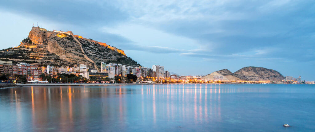 Luces brillantes se reflejan en el agua desde la Costa Blanca española.