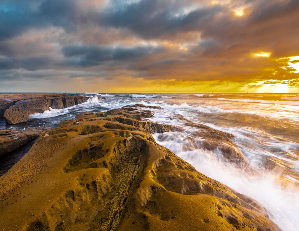 El mar salpica las rocas erosionadas por las olas contra un cielo nublado de California.
