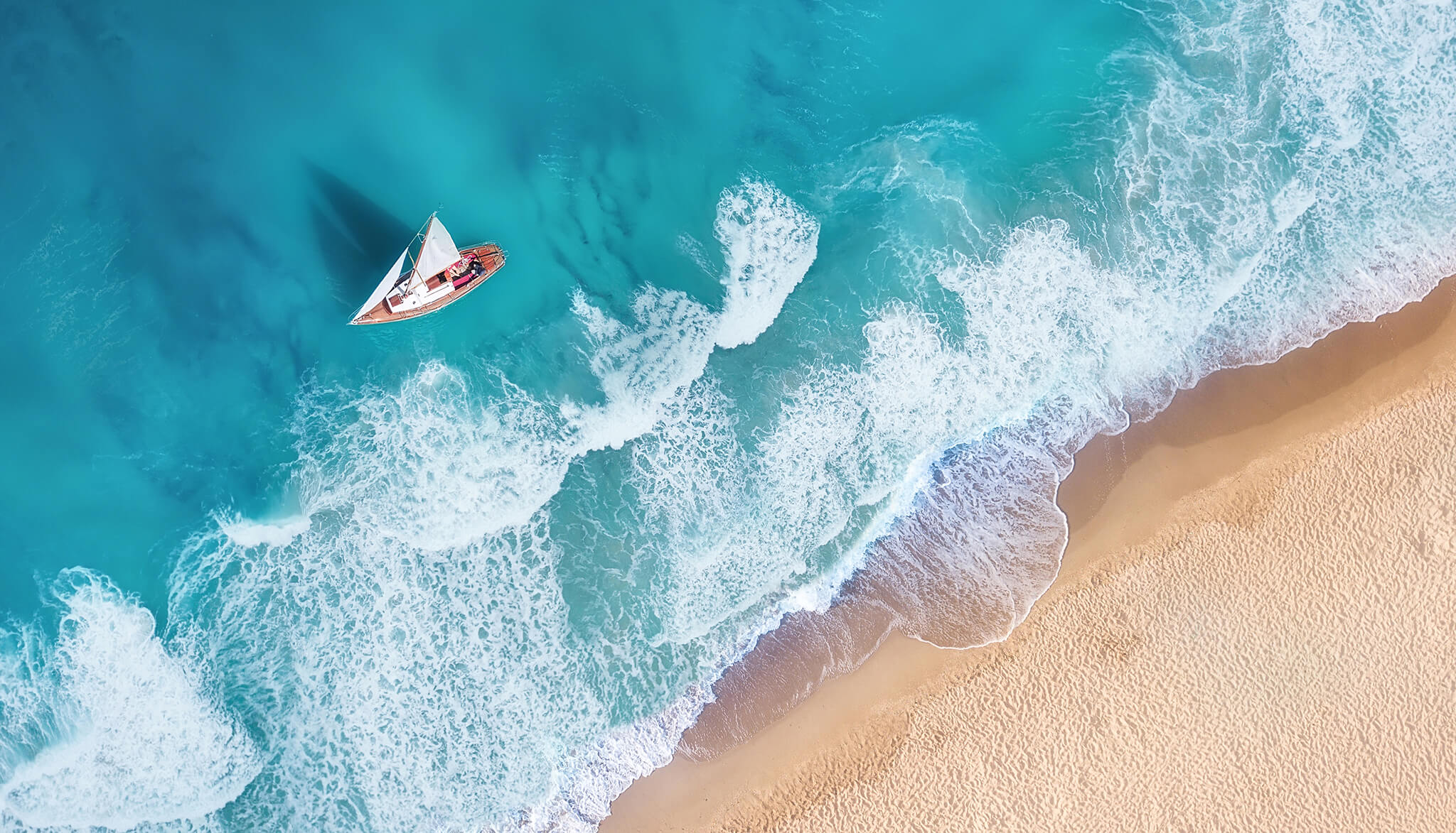 Un velero se desliza entre las olas de una isla caribeña.