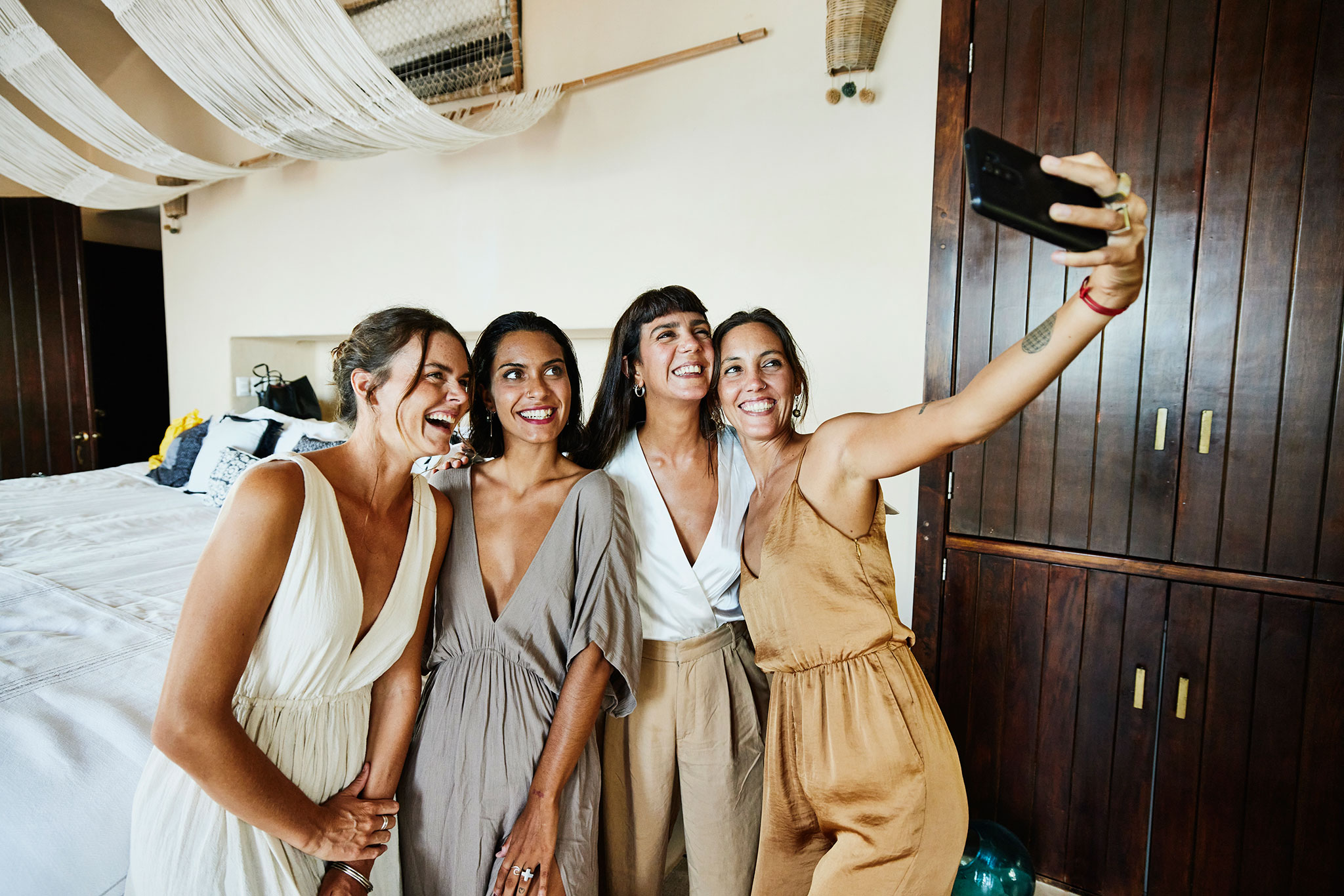 Cuatro amigas posan para un selfi en la suite de un hotel de lujo antes de una boda.