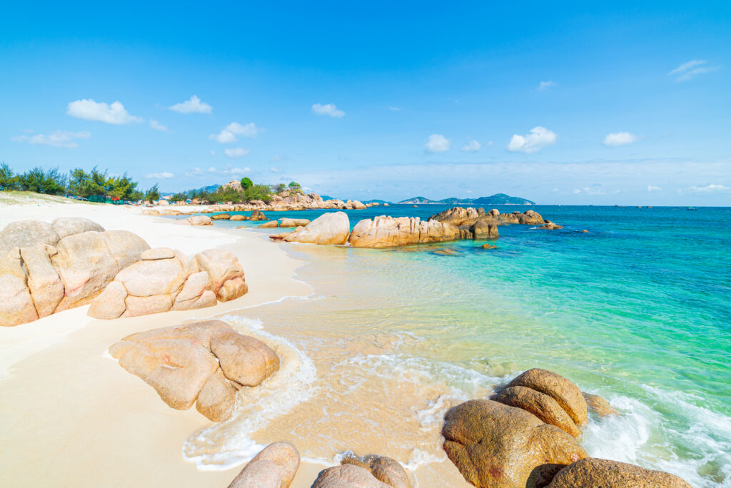 Hermosa playa tropical con aguas de color turquesa transparente y rocas únicas en Cam Ranh, Nha Trang, en la costa sureste de Vietnam, un destino de viaje, una playa desierta sin gente bajo un cielo azul claro.