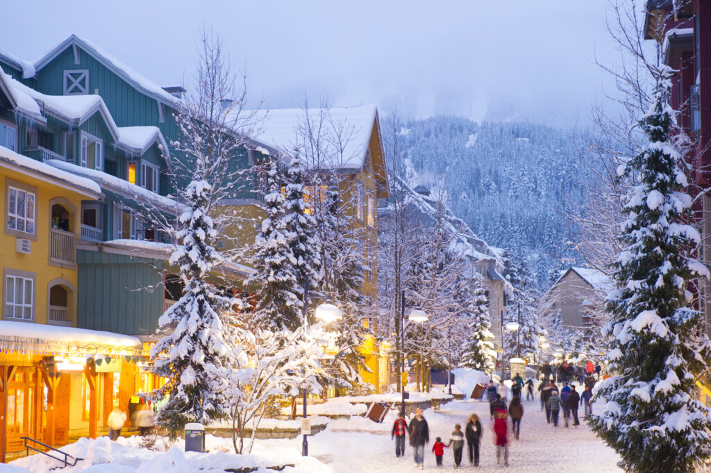 El pueblo peatonal de Whistler, de categoría mundial, repleto de tiendas, hoteles y restaurantes, cubierto de nieve fresca al atardecer.